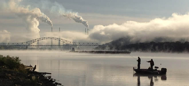 sunrise as fog lift over Ohio River at Lawrenceburg, a boat with man and boy in forground, barge and 275 bridge in background