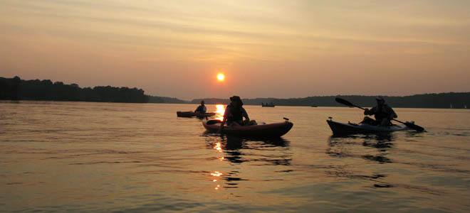kayakers in silohouette against orange sunset at Cowan Lake
